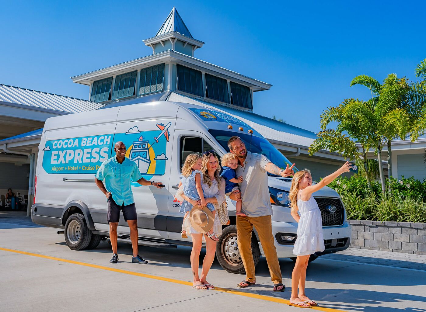 A family with their luggage beside a Cocoa Beach Express van under palm trees.